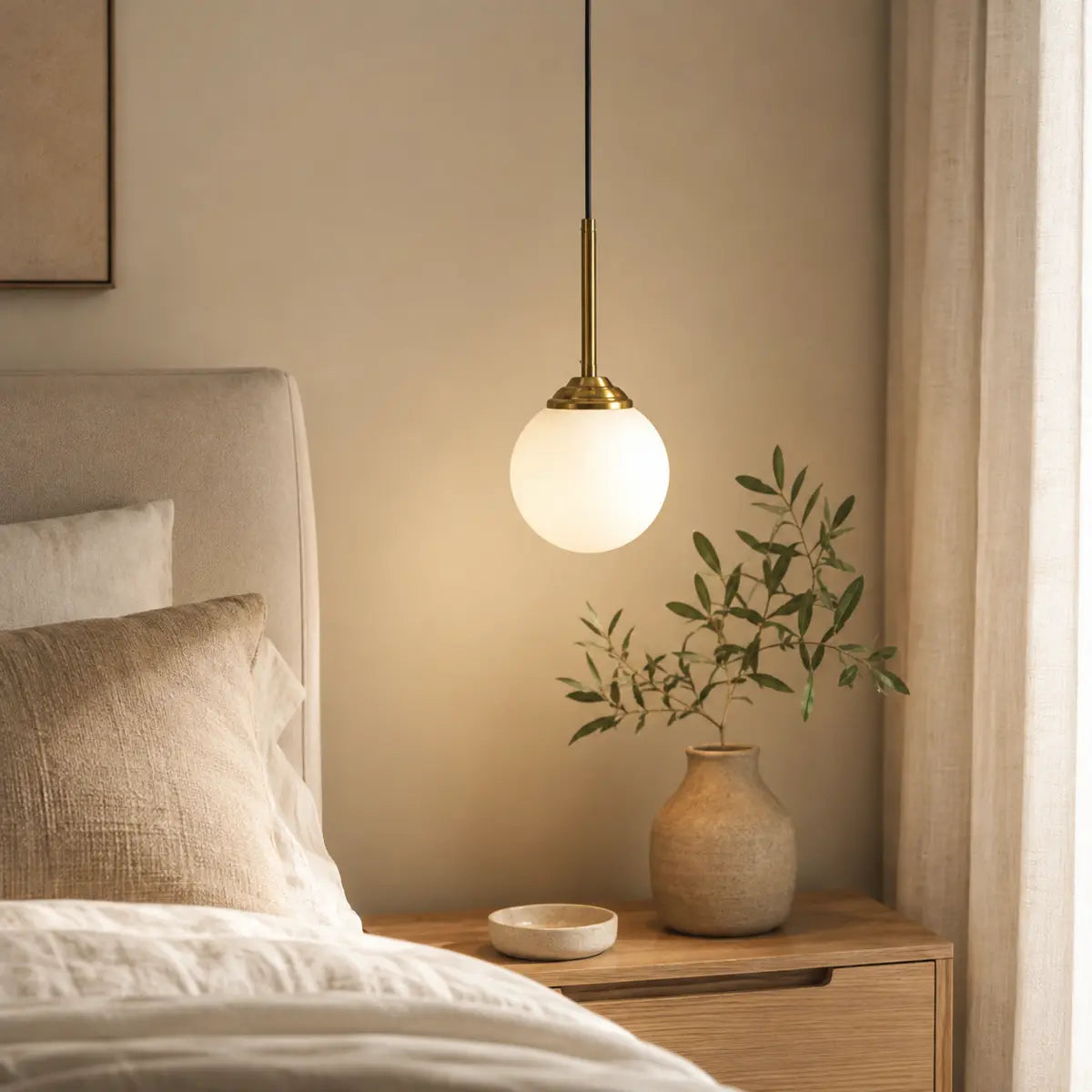 Weiße Glaskugel-Pendelleuchte neben einem Bett im warmen Schlafzimmer