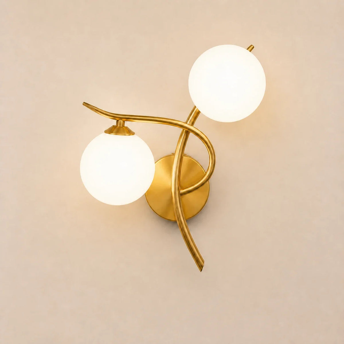 Goldene Glaskugel-Wandleuchte mit rechter Ausrichtung und zwei opalweißen Glaskugeln auf hellem Hintergrund