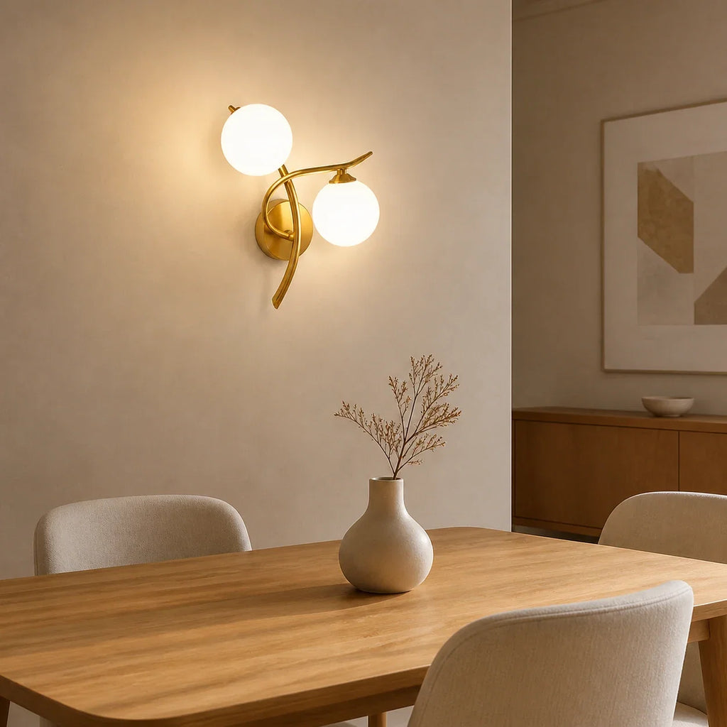 Goldene Glasball-Wandleuchte mit zwei Glaskugeln über einem modernen Esstisch