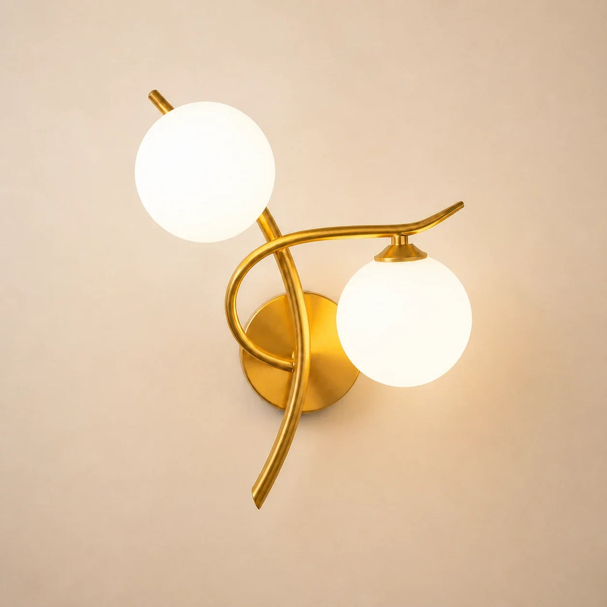 Moderne Glasball-Wandleuchte in Gold mit zwei opalweißen Glaskugeln auf hellem Hintergrund